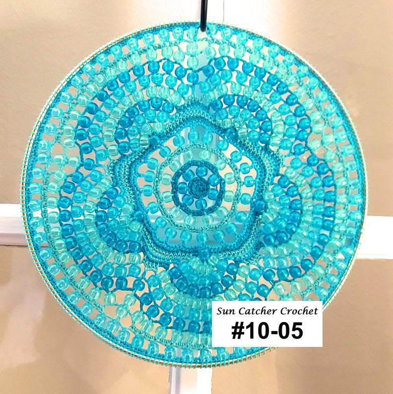 Turquoise beaded sun catcher with a label on a beige background