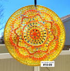 Decorative sun catcher with orange and yellow spiral pattern against a blue sky.
