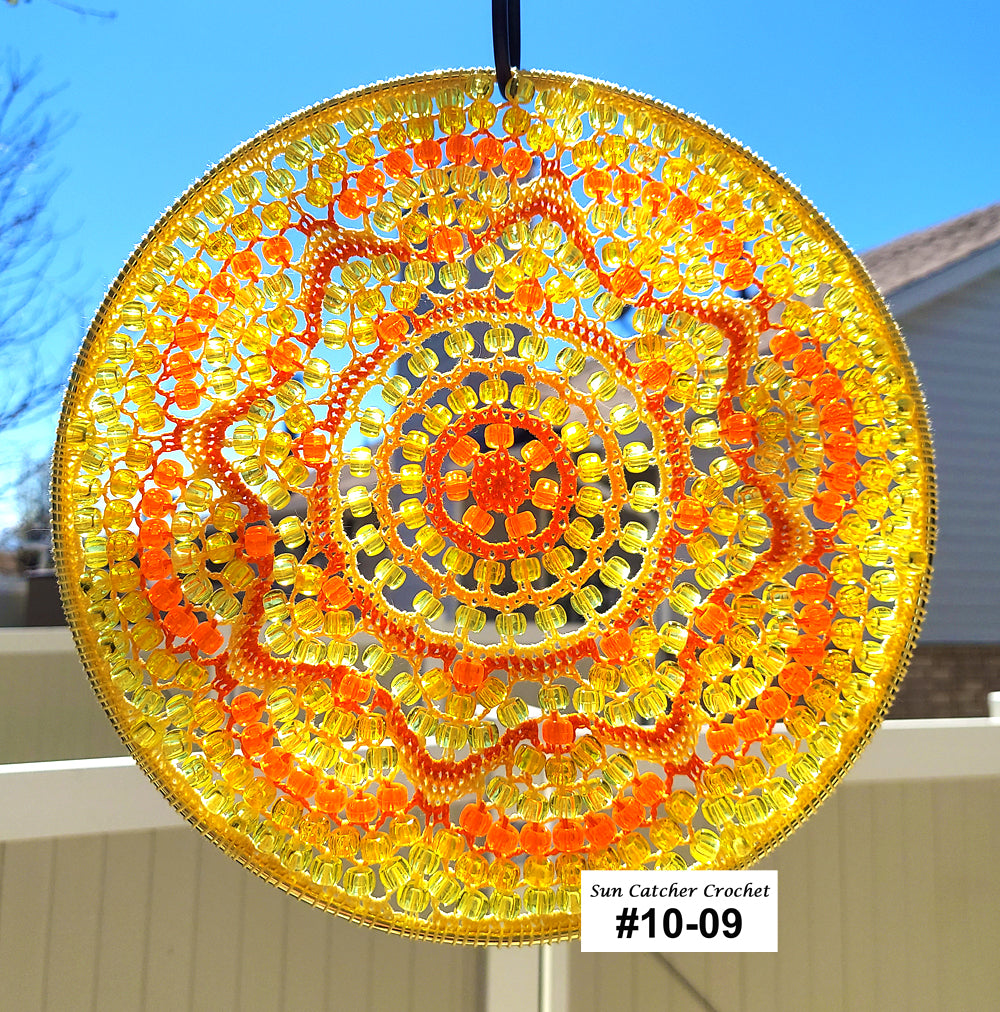 Decorative sun catcher with orange and yellow spiral pattern against a blue sky.