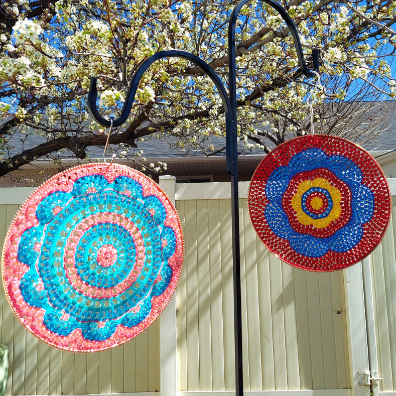 Decorative circular art pieces on a stand with a tree and house in the background