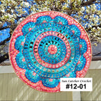 Decorative sun catcher with colorful spiral pattern hanging outdoors.