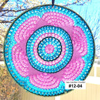 Circular sun catcher with pink and blue spiral pattern against a blurred outdoor background