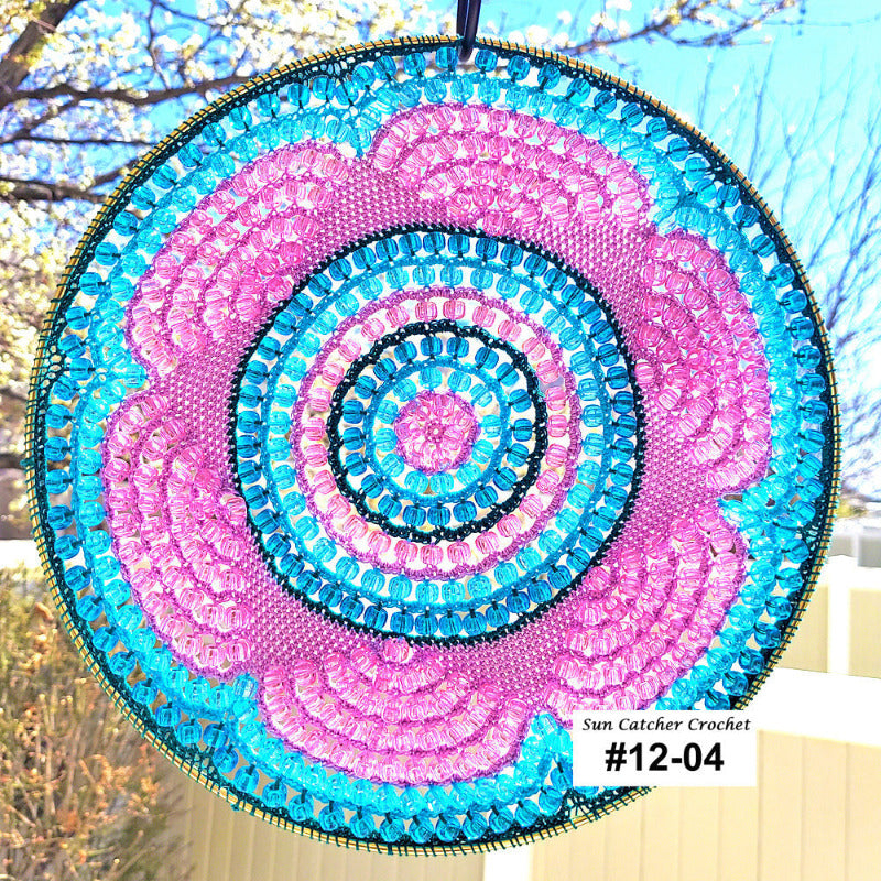 Circular sun catcher with pink and blue spiral pattern against a blurred outdoor background