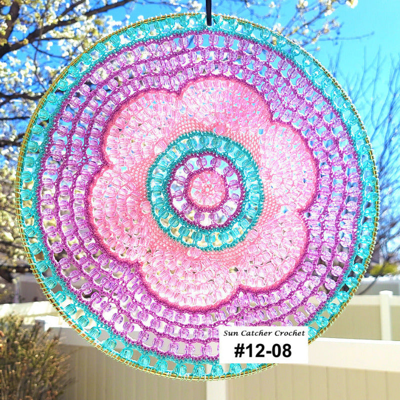 Decorative sun catcher with pink and blue spiral design hanging outdoors.