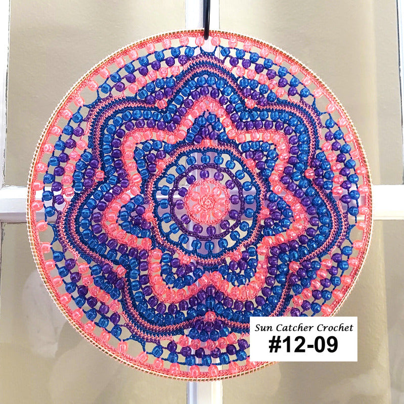 Decorative circular sun catcher with pink and blue patterns on a white background