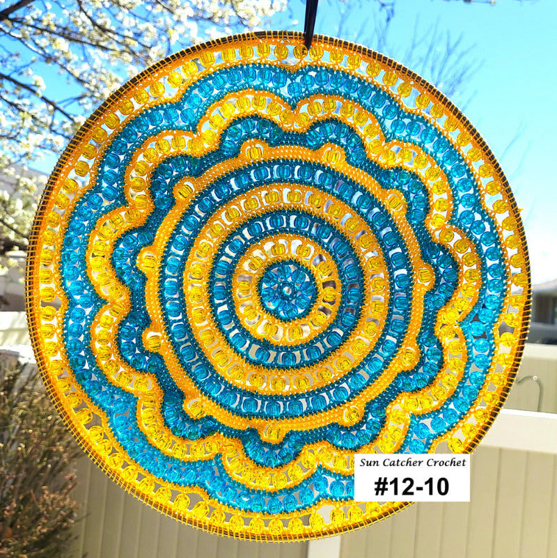 Circular sun catcher with blue and yellow spiral pattern, hanging outdoors.