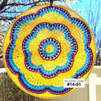 Decorative sun catcher with spiral pattern in yellow, blue, and purple hanging outdoors.