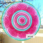 Circular sun catcher with pink and blue spiral pattern hanging outdoors.