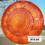Sun catcher crochet item with a spiral pattern against a blue sky and tree background