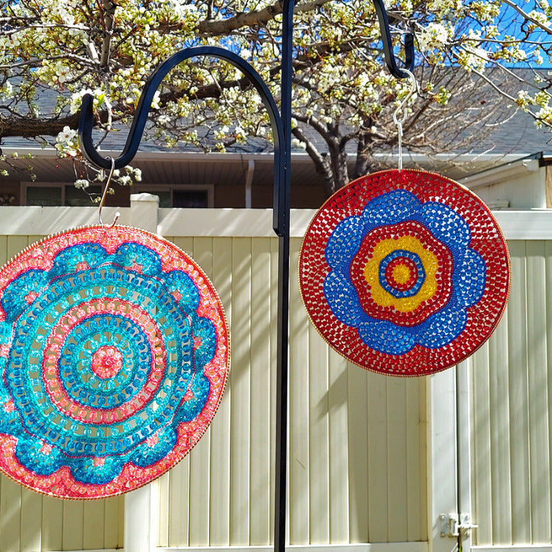 Colorful circular decorations hanging outdoors with a house and tree in the background