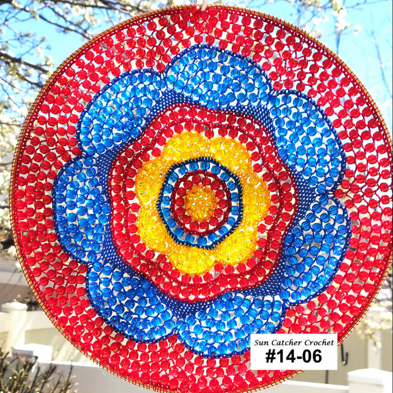 Colorful circular sun catcher with concentric circles of red, blue, and yellow against a blurred outdoor background.