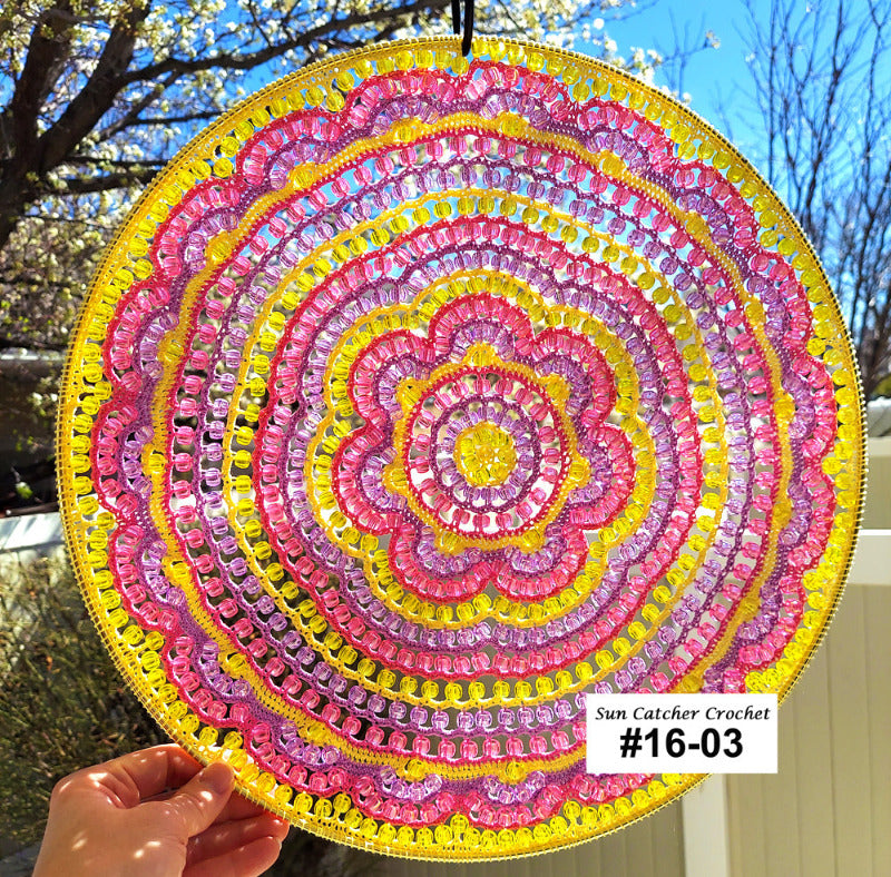 Sun catcher crochet with pink and yellow colors held outdoors.