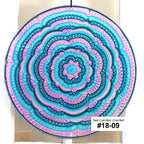 Decorative circular wall hanging with concentric patterns in blue and lilac on a white background.