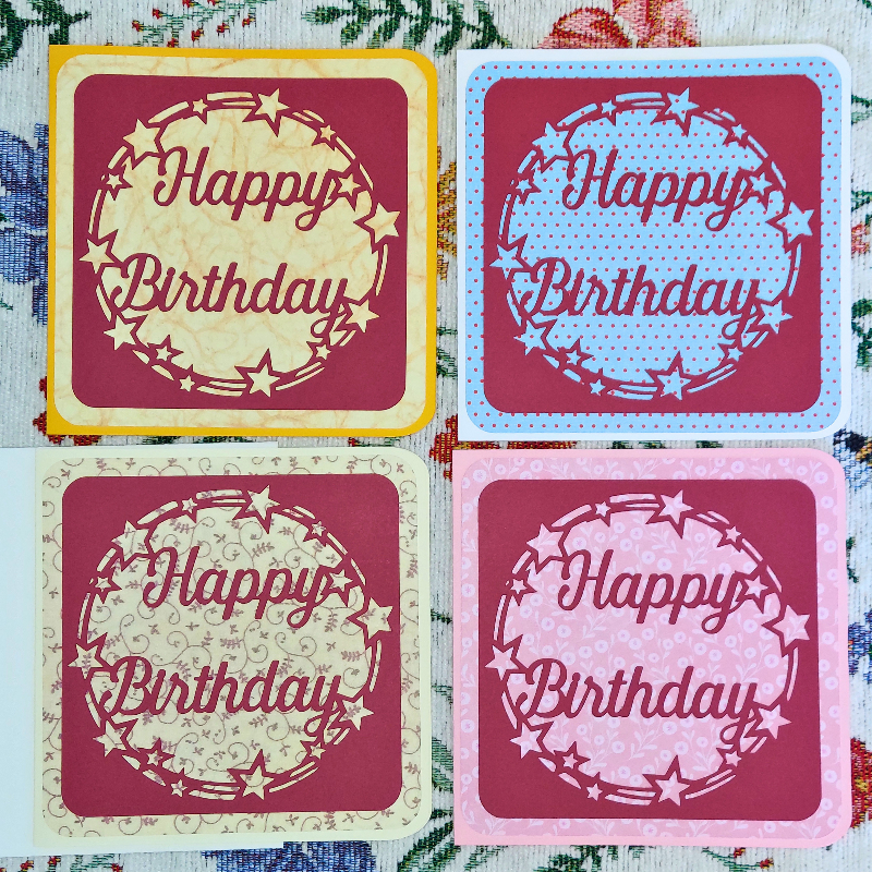Four 'Happy Birthday' cards in different colors on a floral background