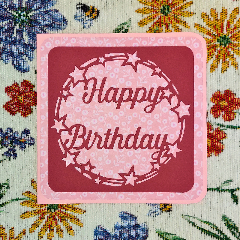 Pink 'Happy Birthday' card with star decorations on a floral background
