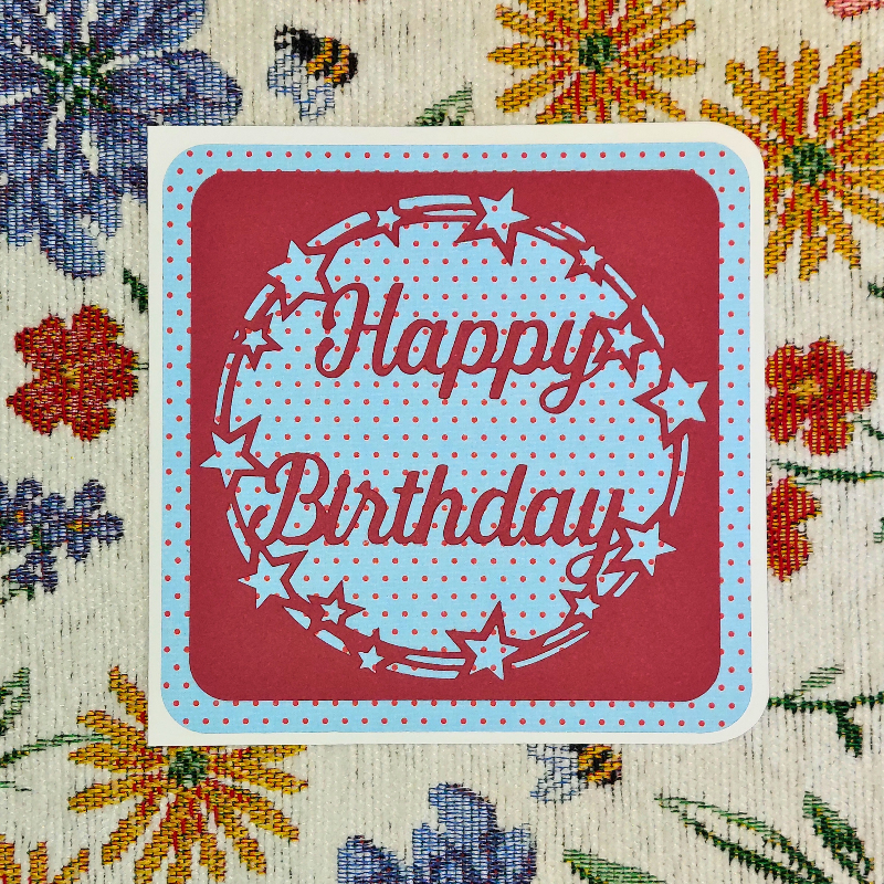 Red card with 'Happy Birthday' text on a floral-patterned background