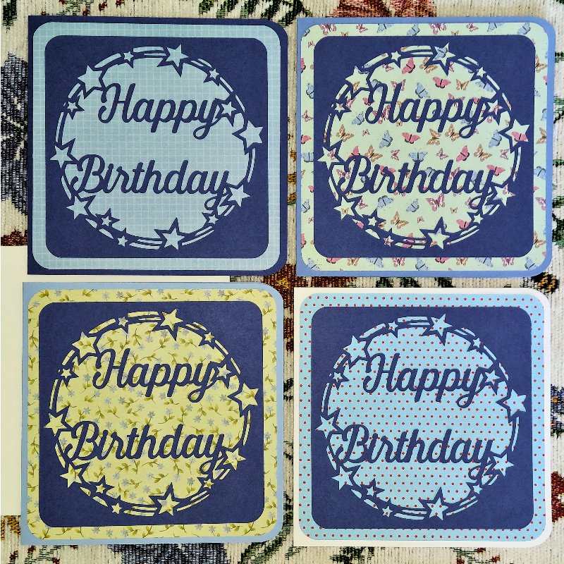Four 'Happy Birthday' cards with decorative wreaths on a textured background