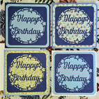 Four 'Happy Birthday' cards with decorative wreaths on a textured background