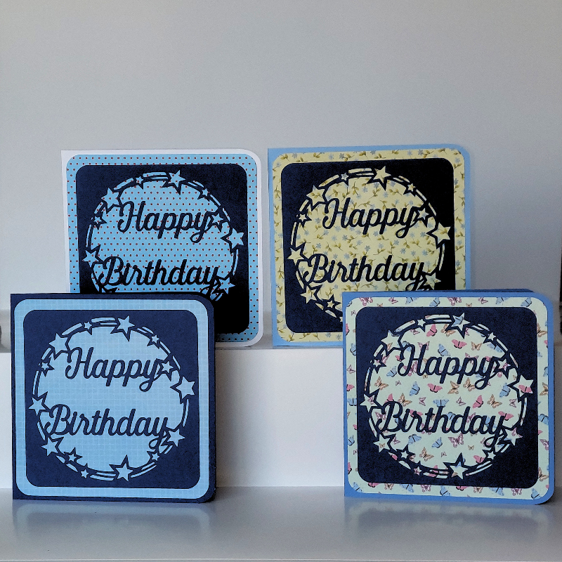 Four 'Happy Birthday' greeting cards with decorative patterns on a white surface.