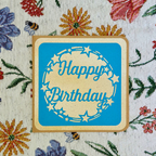 Happy Birthday card with blue background and beige border on floral fabric