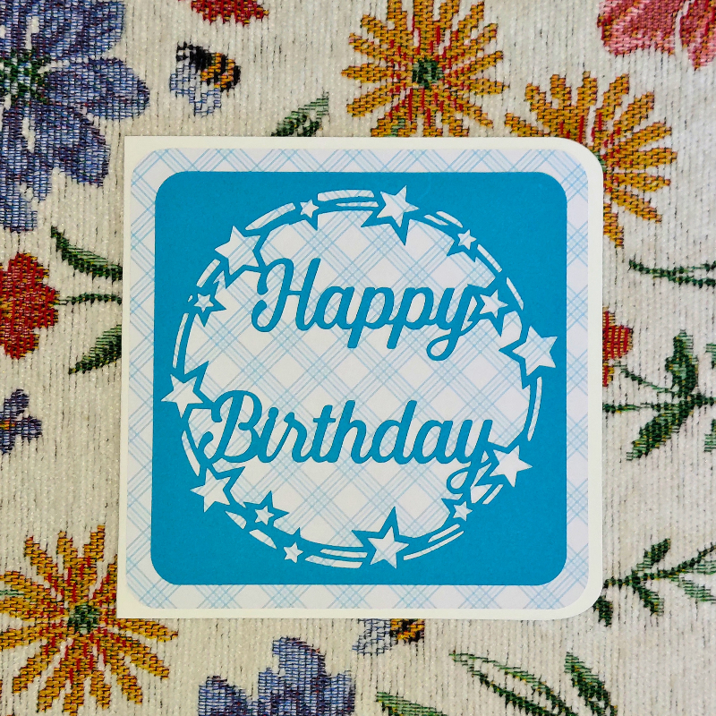 Blue 'Happy Birthday' card on a floral fabric background