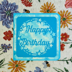 Blue 'Happy Birthday' card on a floral fabric background