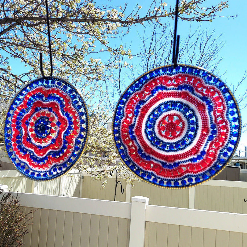 Two circular decorative items with red, white, and blue patterns hanging outdoors against a clear sky.