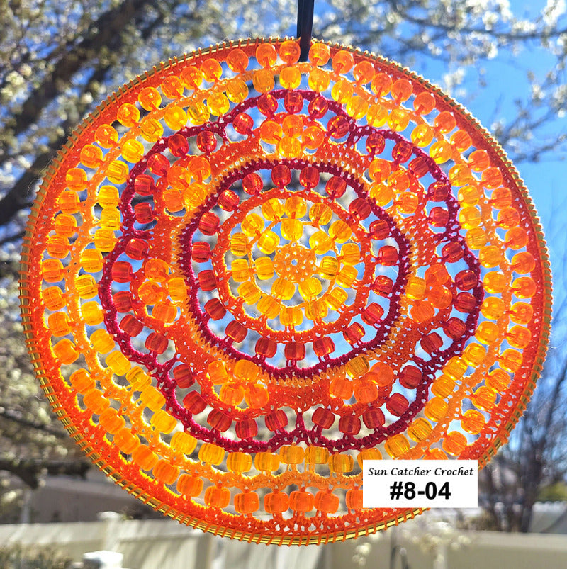 Circular sun catcher with orange and red pattern against a blurred outdoor background