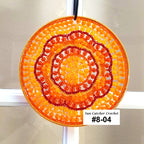 Decorative sun catcher with orange and red spiral design on a white background