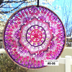 Circular beaded sun catcher with pink and purple colors hanging outdoors.
