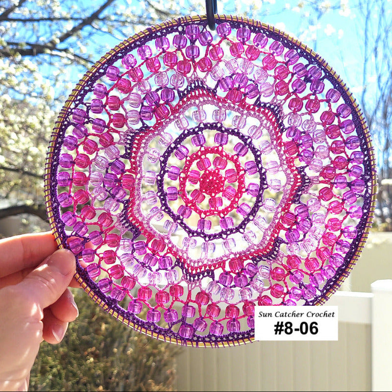 Handmade sun catcher with pink and purple spiral pattern held outdoors.