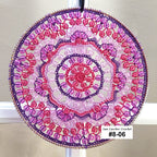 Circular beaded sun catcher with pink and purple colors on a white background
