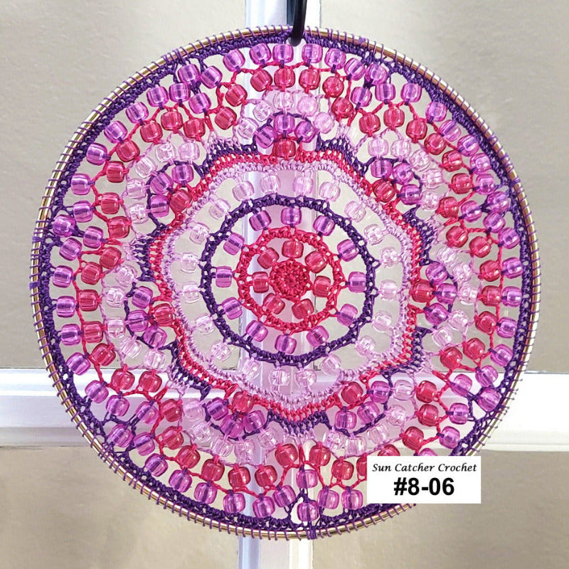 Circular beaded sun catcher with pink and purple colors on a white background