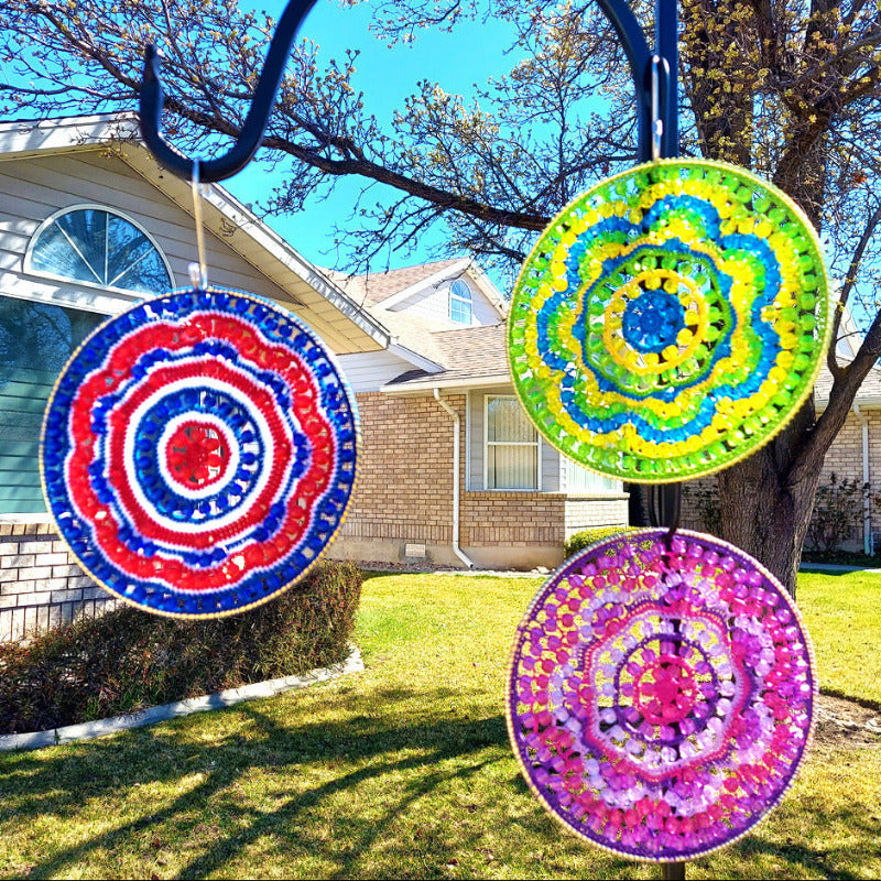 Colorful circular decorations on a stand outdoors with a house and tree in the background.