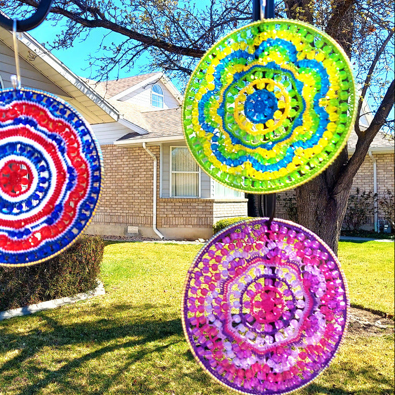 Colorful circular decorations on a stand outdoors with a house and tree in the background.