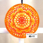 Round sun catcher with orange and yellow pattern on a white background