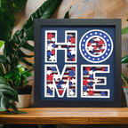 Framed decorative sign with 'HOME' in American flag pattern on a wooden surface with plants.