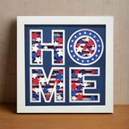 Framed decorative wall art with 'HOME' design featuring American flag colors on a wooden surface.