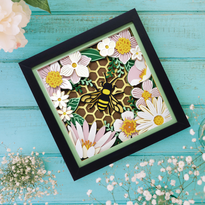 Decorative wall art with a bee and flowers on a teal wooden background