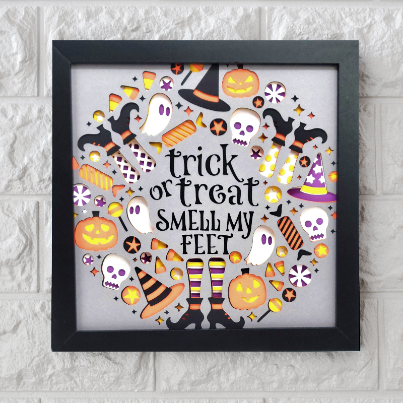 Framed Halloween-themed artwork with text and icons on a white brick wall background