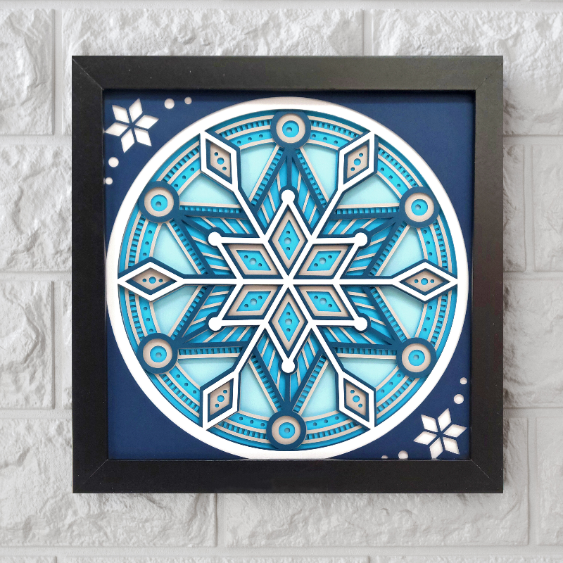 Decorative snowflake design in a black frame on a textured white wall.