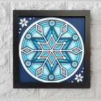 Decorative snowflake design in a black frame on a textured white wall.
