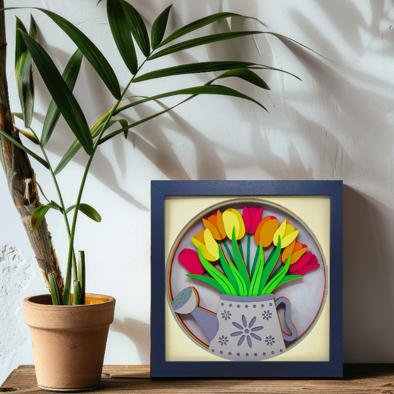 Framed artwork of colorful tulips next to a potted plant on a wooden surface.