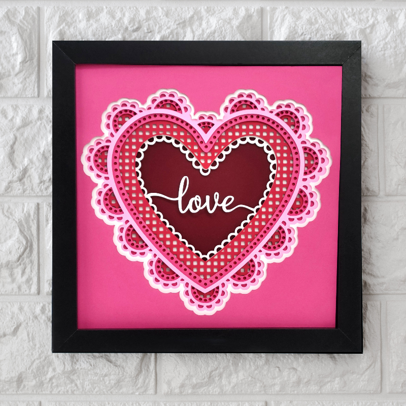 Heart-shaped decorative item with 'love' text on a pink background, framed in black.