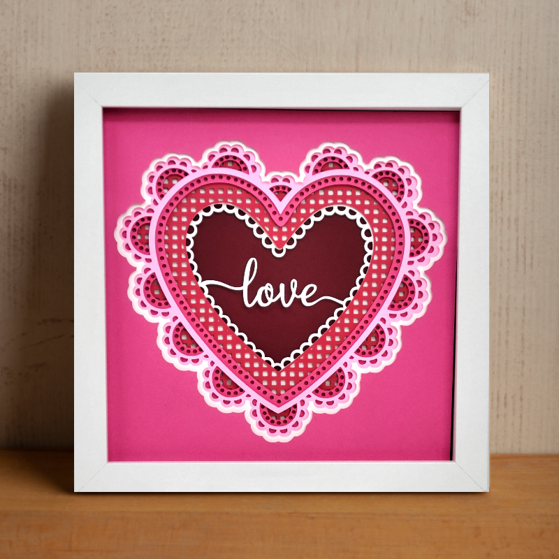 Framed heart-shaped artwork with 'love' text on a pink background