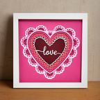 Framed heart-shaped artwork with 'love' text on a pink background