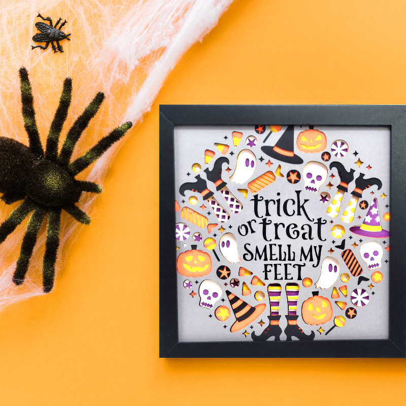 Framed Halloween-themed artwork with text and decorations on an orange background.