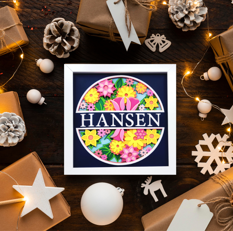 Framed floral design with 'Hansen' text on a festive wooden background with gifts and decorations.