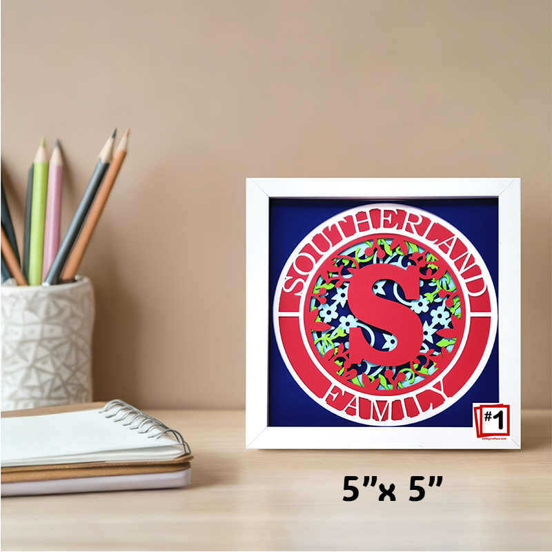 Framed artwork with a colorful letter 'S' design on a desk with stationery items.