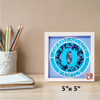 Framed artwork with a blue circle design on a desk with stationery items.